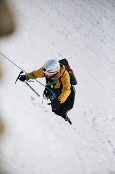 A climber tackles a snowy incline using an ice axe on a sunny winter day.