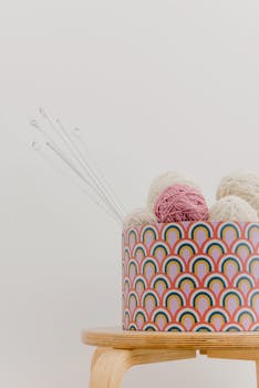 Abstract rainbow-patterned box with colorful yarn balls and knitting needles.