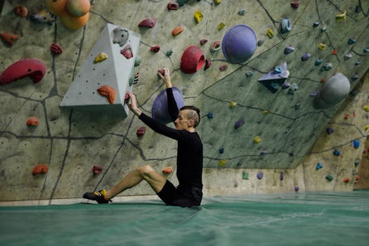 Amputee athlete bouldering indoors, demonstrating adaptability and strength.