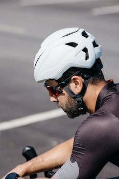 Close-up of a focused cyclist wearing a helmet and sunglasses while riding.