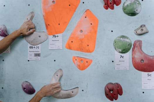 Hands gripping colorful climbing holds on an indoor climbing wall, highlighting strength and technique.