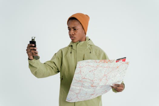 Portrait of a young man navigating with a map and a device, expressing adventure and exploration.