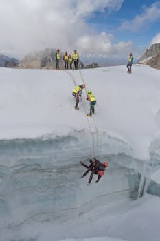 Team conducting a high-altitude rescue on a snowy mountain with safety gear.